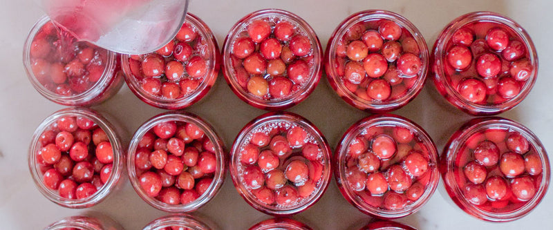 Bocaux de fruits rouges dans le sirop en pleine préparation à la confiserie. 